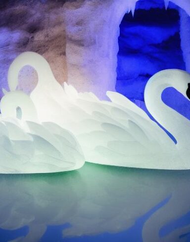 An tranquil ice sculpture of two glowing ice-made swans on a wave