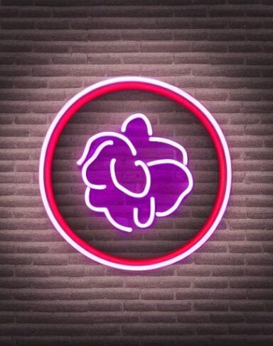 A small purple flower neon sign on a brick wall